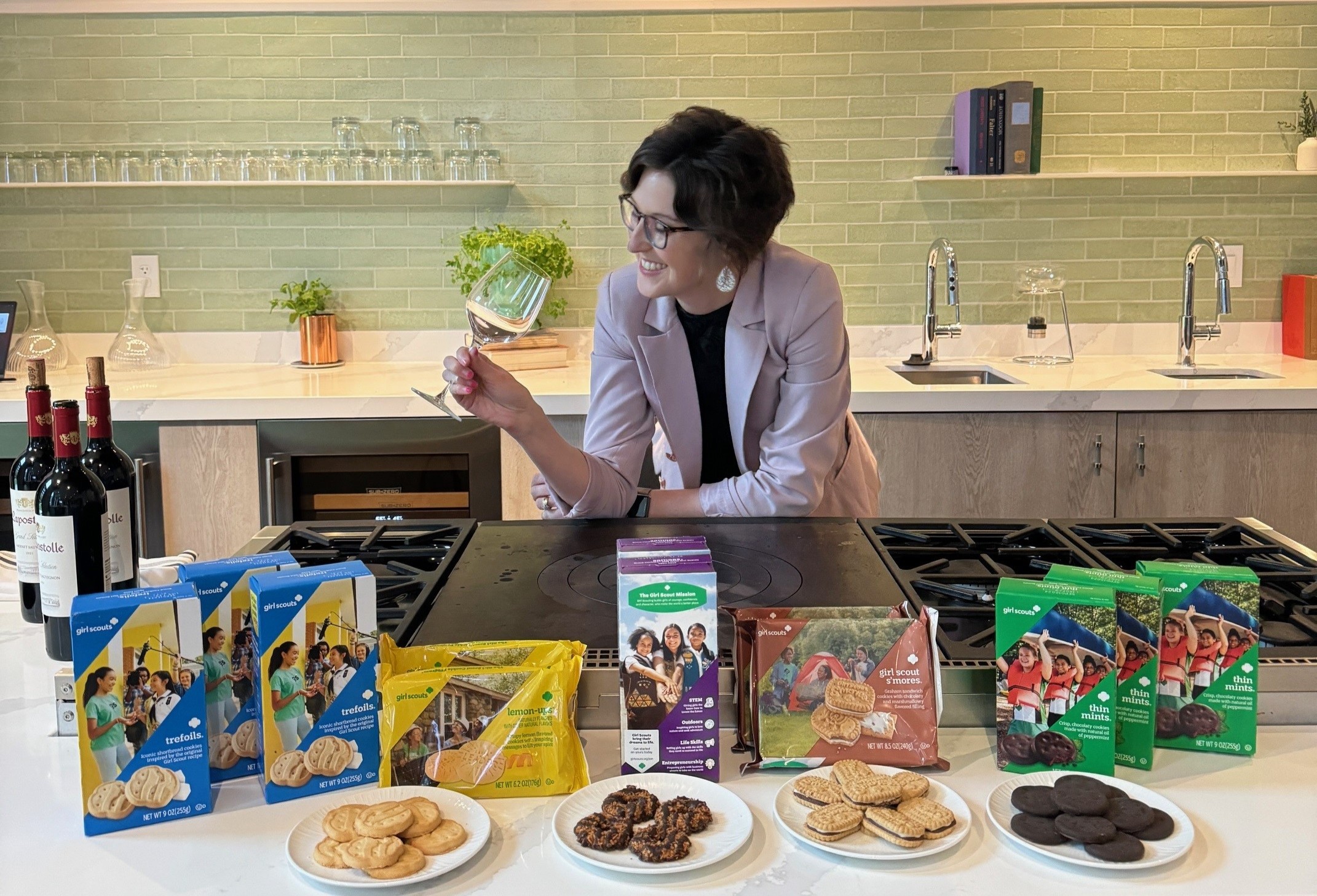a woman holding a wine glass with a table full of Girl Scout cookies for pairing at Epicurean Hotel in Midtown Atlanta